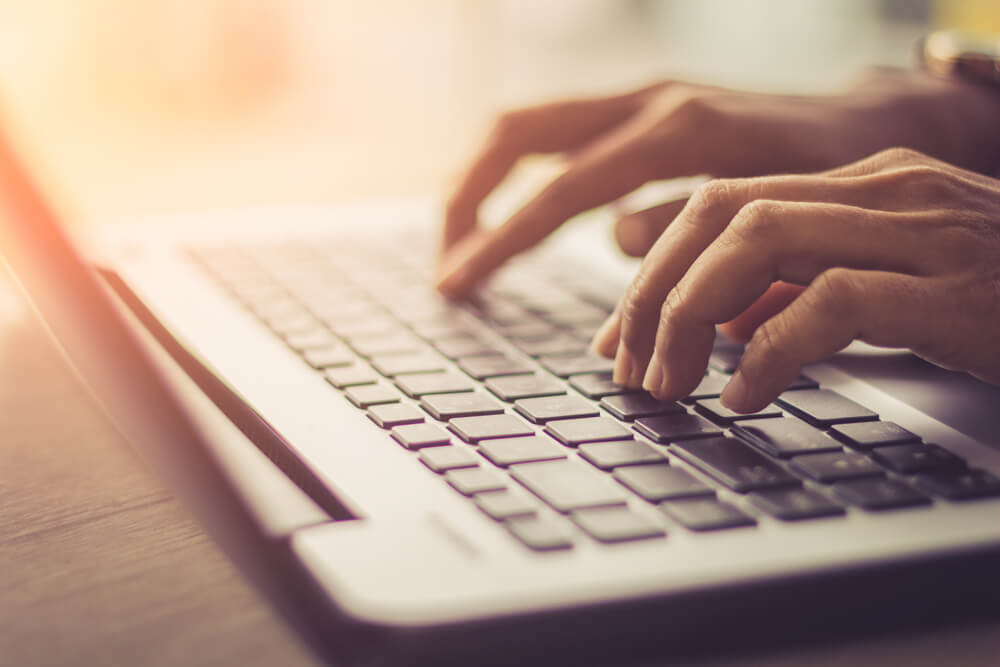 closeup of hands typing on laptop