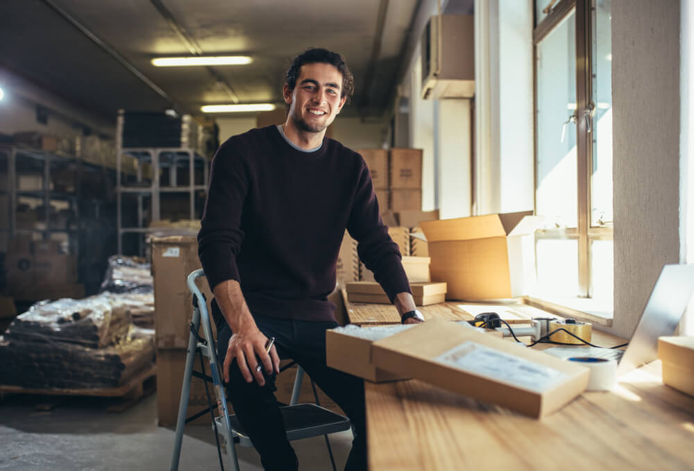 smiling young male entrepreneur with warehouse background