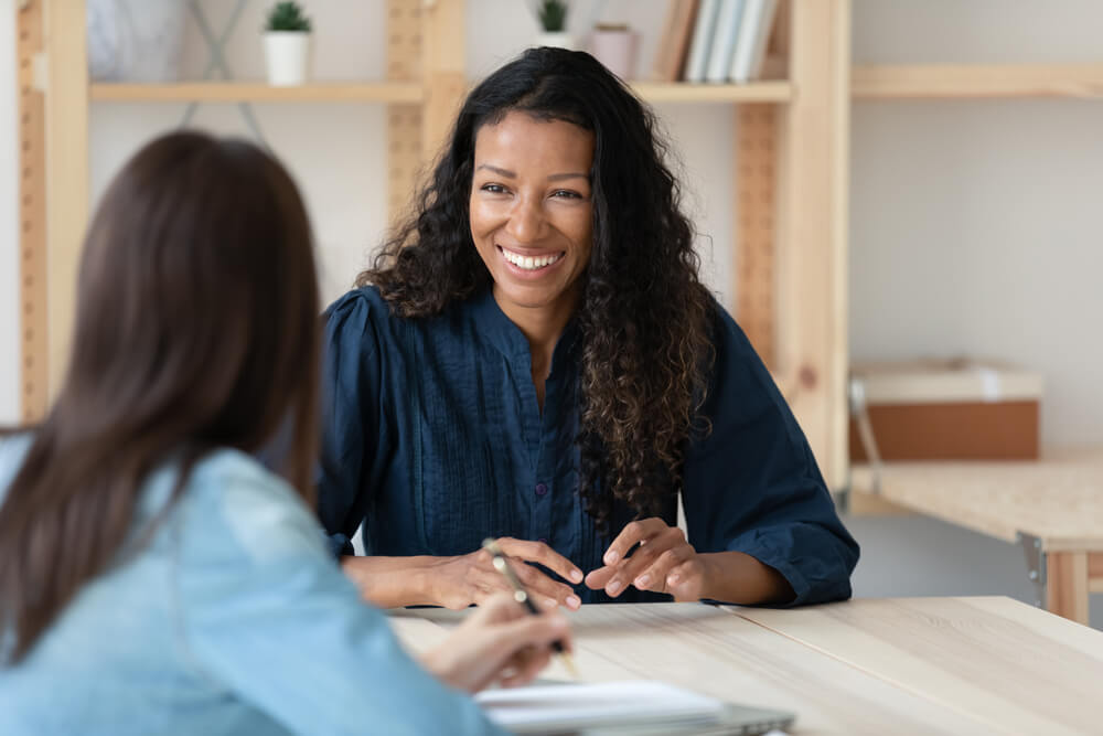 smiling young woman talking to blurred female professional