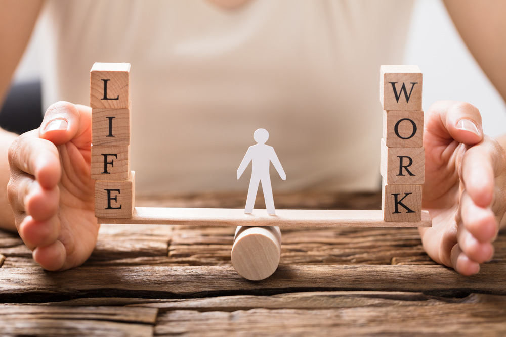 Close-up Of A Human Hand Protecting Balance Between Life And Work On Seesaw