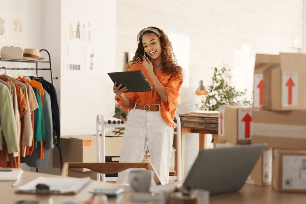 female owner of small ecommerce startup on the phone and holding tablet