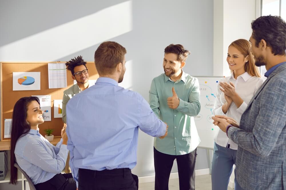 male coach shaking hands with male employee in group